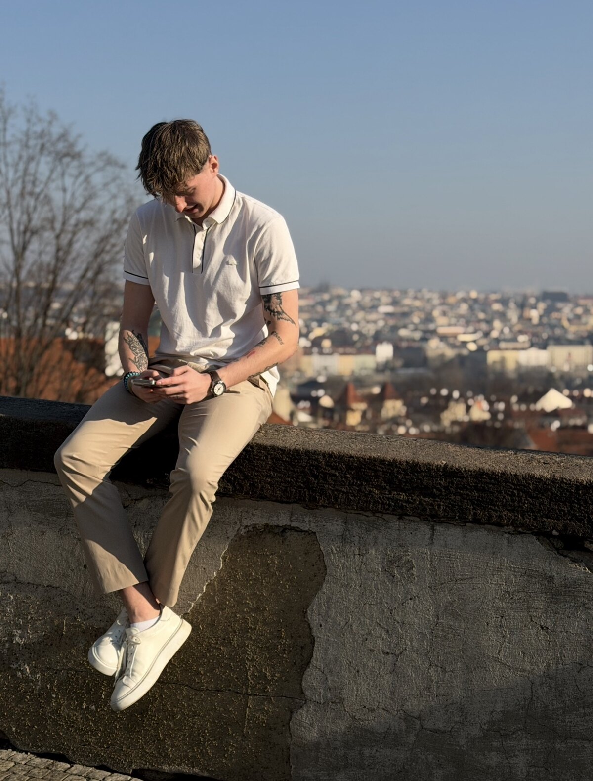 Dominik sedící na zdi s výhledem na Prahu